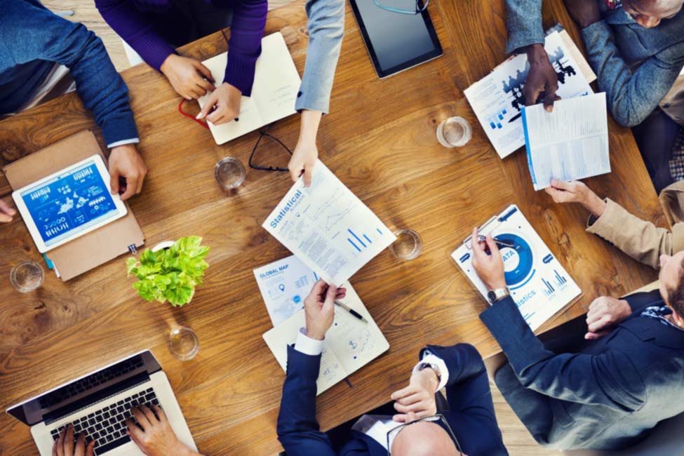 Bird's eye view of people meeting around a table with project documents