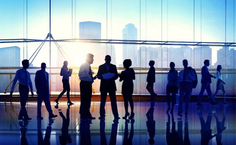 Silhouettes of business people collaborating in front of tall windows