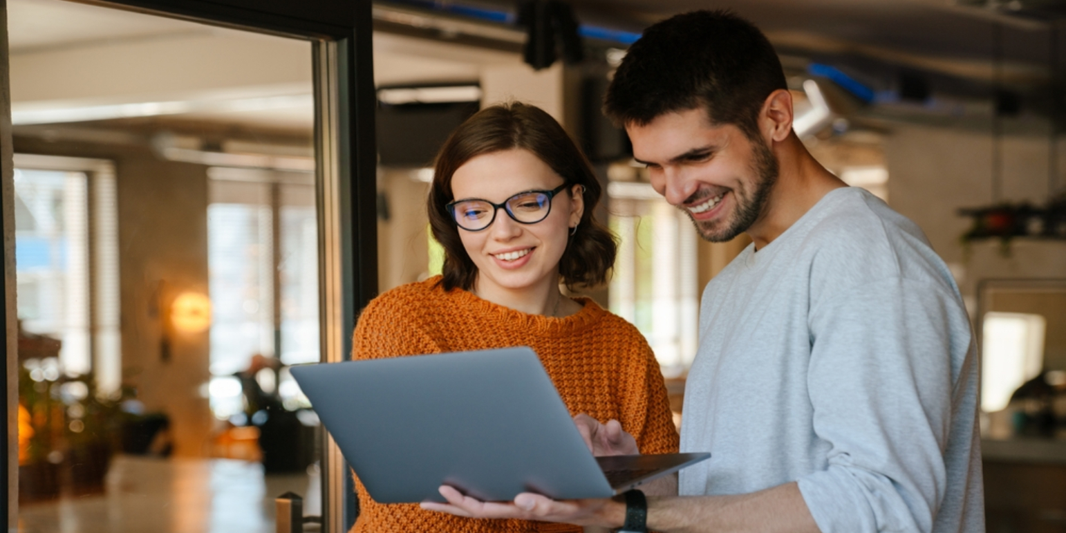 Two people looking at a laptop discussing work